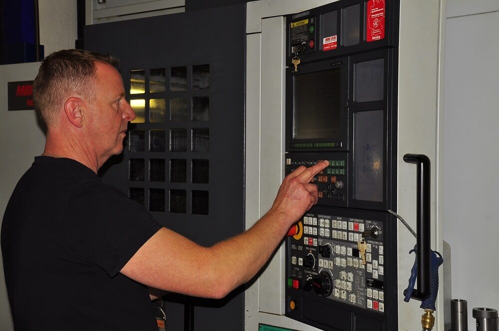 Ein Feinwerkmechaniker programmiert eine CNC-Maschine Ein Feinwerkmechaniker programmiert eine CNC-Maschine