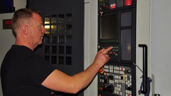Ein Feinwerkmechaniker programmiert eine CNC-Maschine Ein Feinwerkmechaniker programmiert eine CNC-Maschine